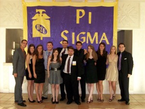 A group of people standing in front of PI Sigma sign