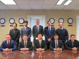 A group of people sitting and standing behind a table