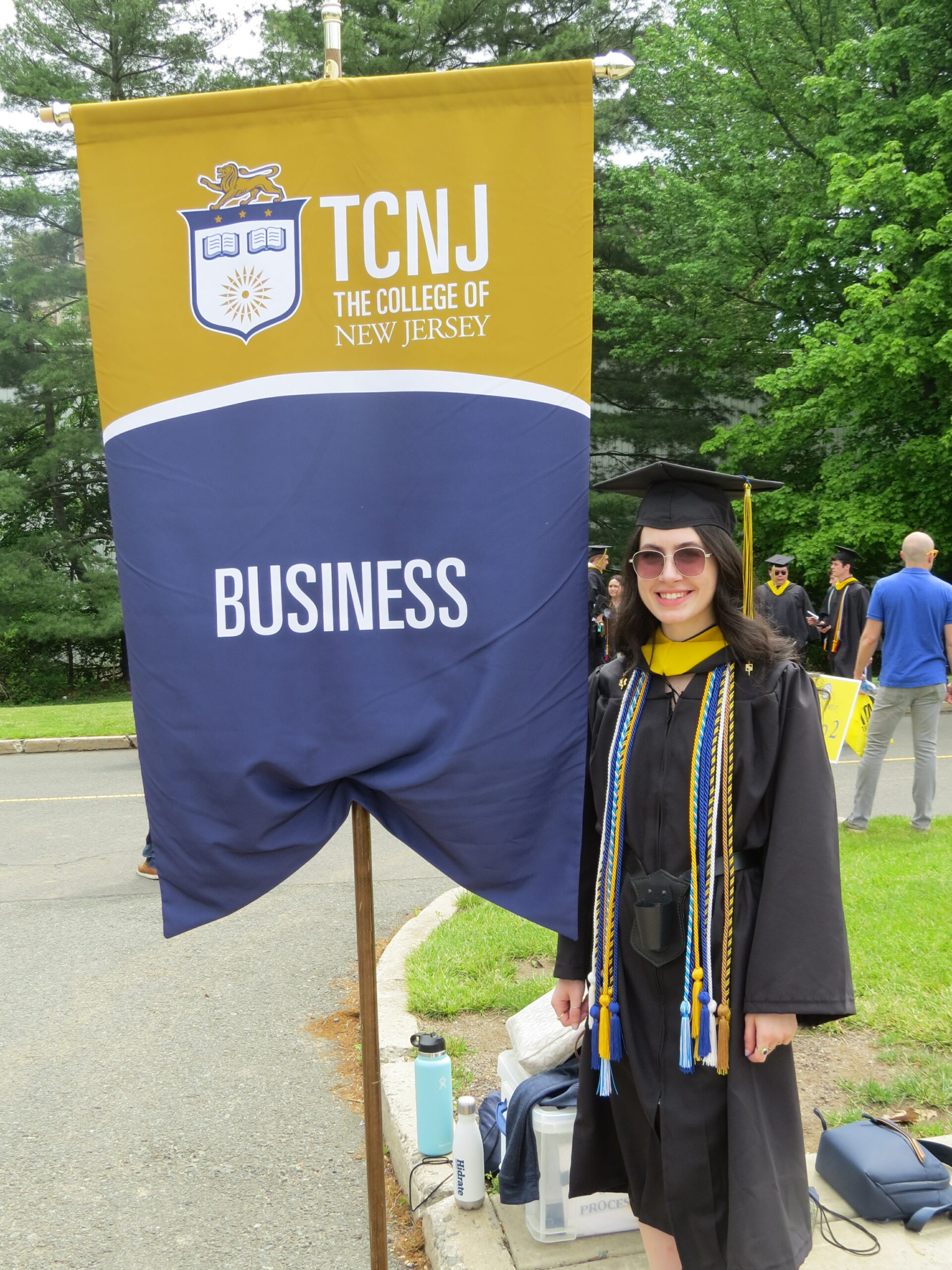 TCNJ student next to the business sign
