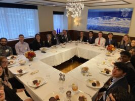 People sitting around a rectangular table with plates of food in front of them