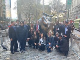 A group of students standing next to a bull statue