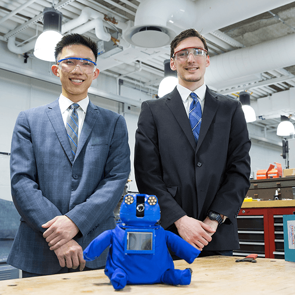 Two people standing next to each other behind a robot